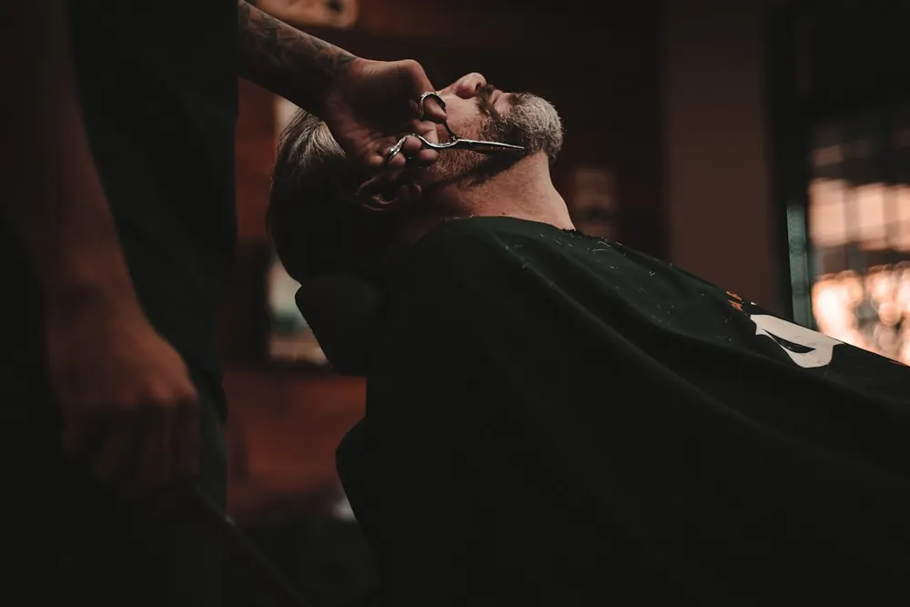Un barbero rematando un degradado bajo la luz cálida del local